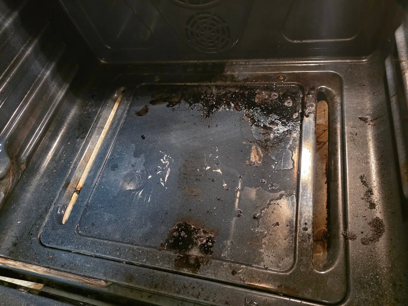 An oven interior heavily soiled with baked-on grime, before a PureMind deep clean
